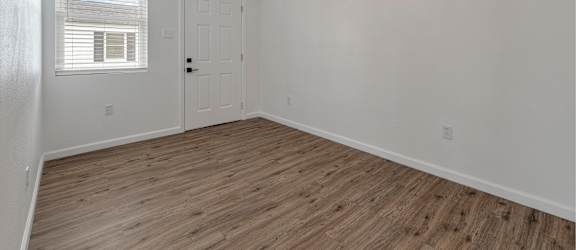 an empty living room with a ceiling fan and a door
