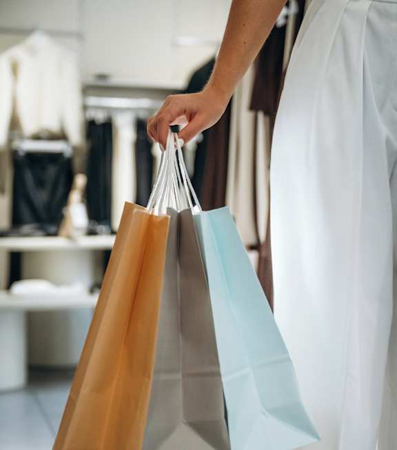 A person holding shopping bags in a clothing store.
