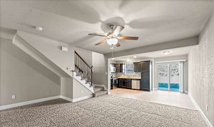 A spacious room with a staircase and a ceiling fan.