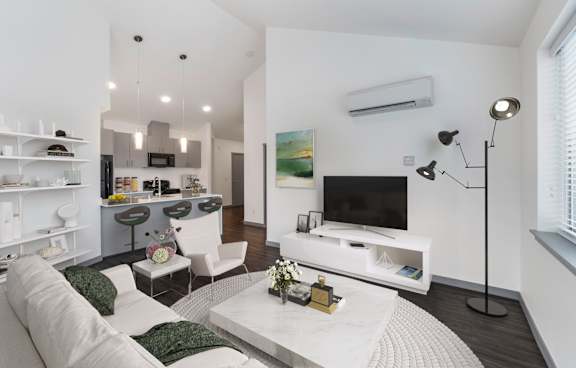 A modern living room with a white sofa, a white coffee table, and a white kitchen in the background.