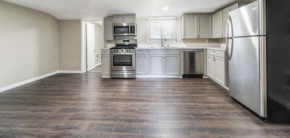 an empty kitchen with stainless steel appliances and white cabinets