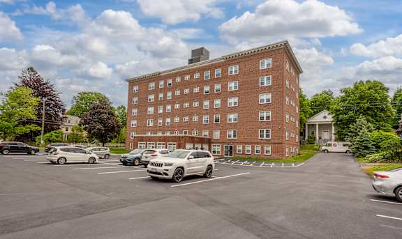 A parking lot with cars and a red brick building in the background.