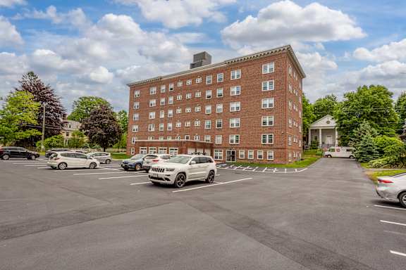 A parking lot with cars and a red brick building in the background.