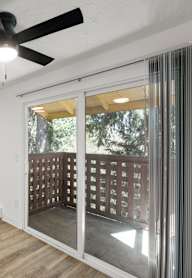 A room with a ceiling fan and sliding glass doors.