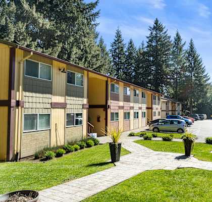 A sunny day in a residential area with apartment buildings and a parked car.