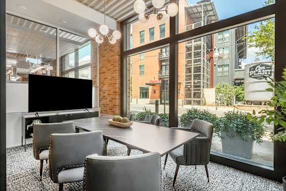 Meeting room large window and a table with chairs and a television The Can Plant, San Antonio Luxury Apartments