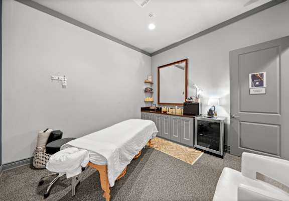 A room with a massage table and a mirror on the wall.