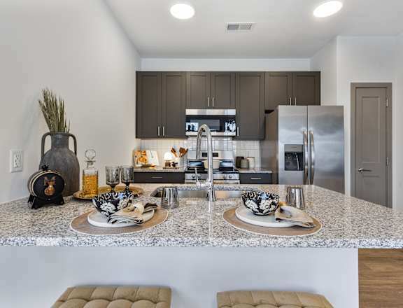 A modern kitchen with a marble countertop and stainless steel appliances.
