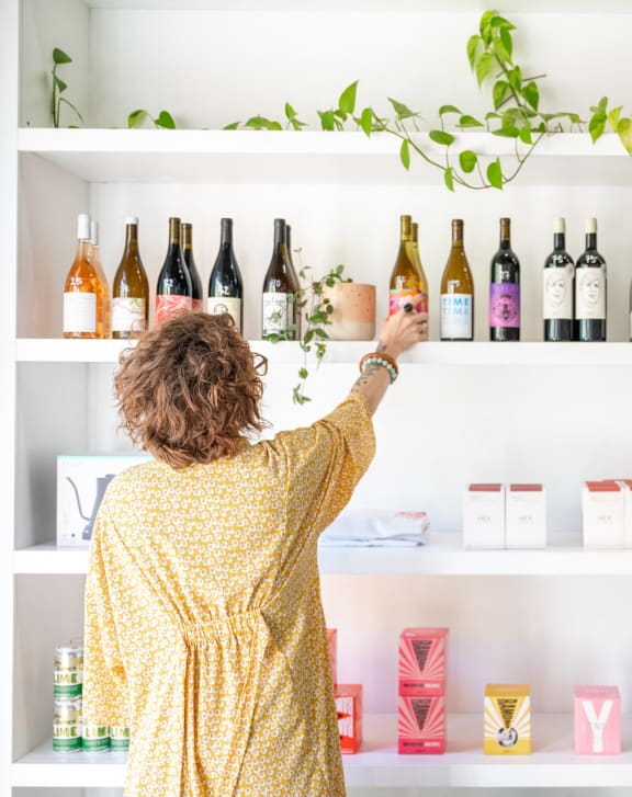 a woman putting a bottle of wine on a shelf