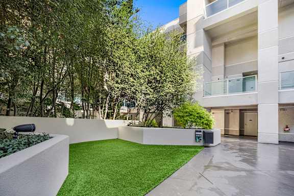 A modern courtyard with a green lawn and trees. at Esprit Apartments, California, 90292