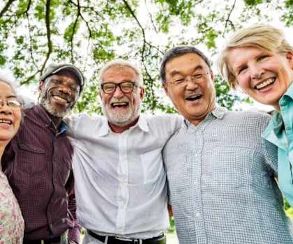 A group of five people stand together in a park.