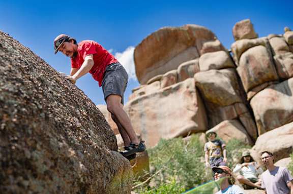 A man climbs a rock in a group of people.