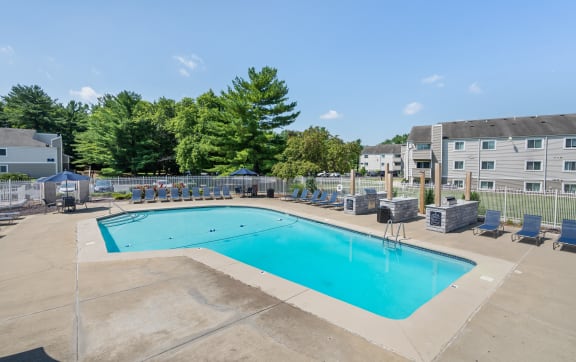 a large pool with lounge chairs and umbrellas in front of a building at Candles, Springfield, 62704
