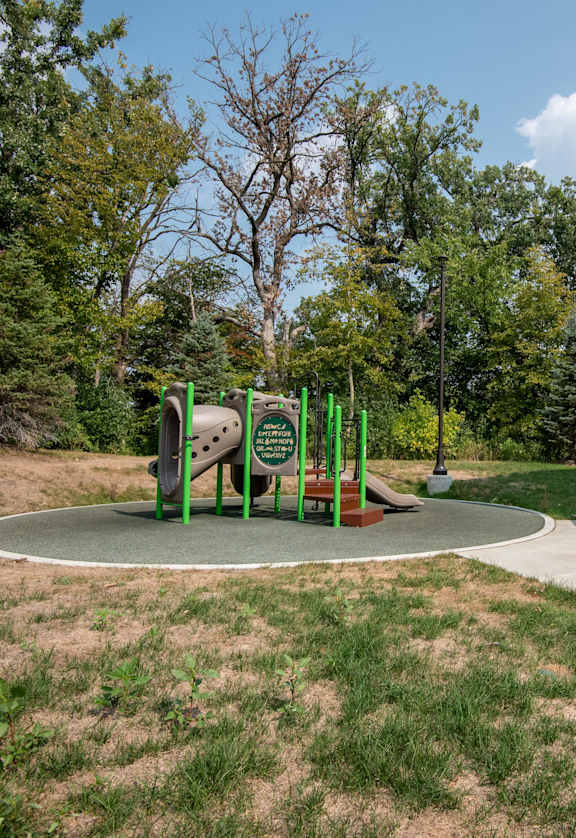 A playground with a green slide and a brown bench.
