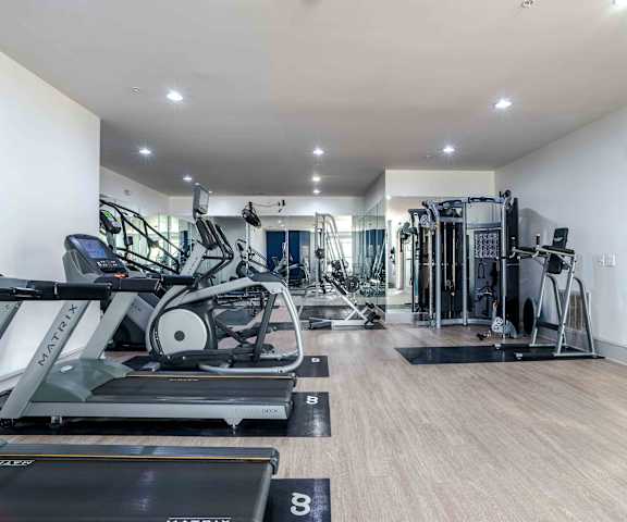 A spacious gym with a variety of equipment including treadmills, elliptical machines, and weight machines.