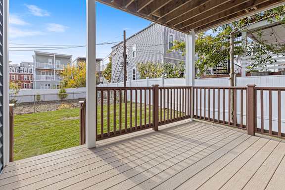 A wooden deck with a railing and a view of a residential area.