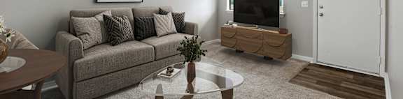 A living room with a grey couch, a coffee table, a ceiling fan, and a television.
