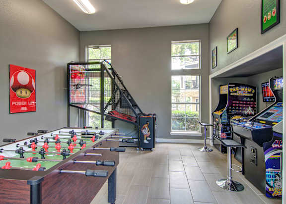 A room with a foosball table and arcade games.