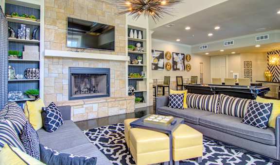 A living room with a grey couch and a yellow ottoman.
