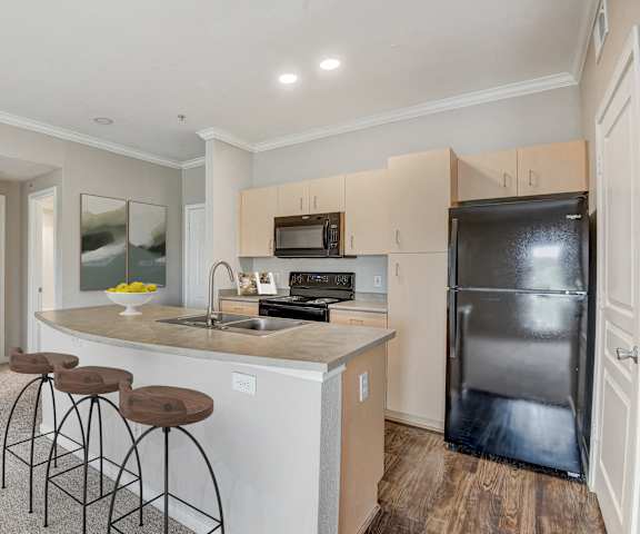 a kitchen with a large island with three stools at Artisan Apartments & Shops, Austin