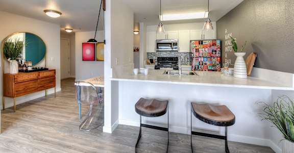a view of a kitchen and a living room with a bar and stools