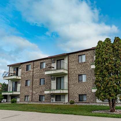 a brick apartment building with balconies and a tree. Fargo, ND Hawthorn Apartments