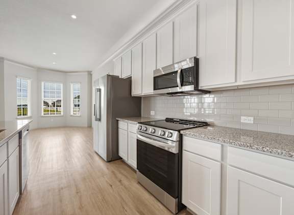 A kitchen with white cabinets and a black stove top oven.