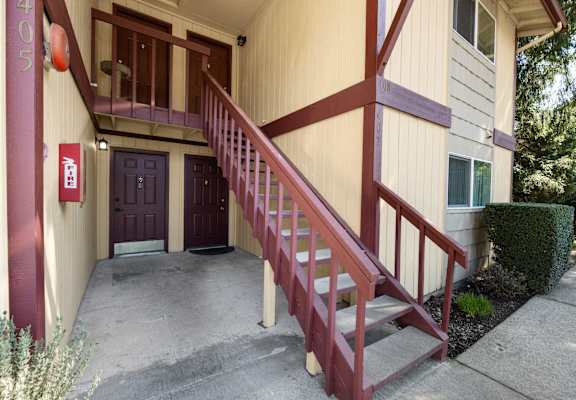 A building with a red door and a staircase leading to the second floor.