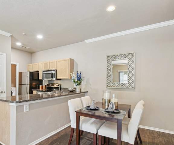 a dining room with a table and chairs next to a kitchen with a counter top
