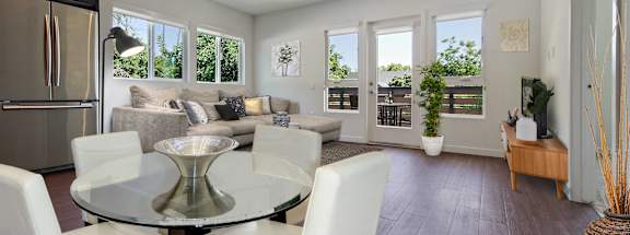 A modern dining room with a glass table and white chairs.