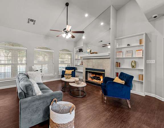 A chic and welcoming clubhouse lounge with a cozy fireplace, plush seating, built-in bookshelves, and contemporary, warm décor.
