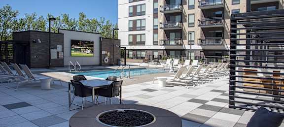 A modern outdoor pool area with a hot tub and lounge chairs.