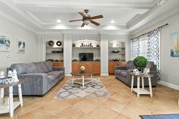 A living room with a grey couch, a white coffee table, and a ceiling fan.