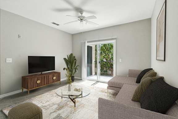 A living room with a grey couch, a coffee table, and a flat screen TV.