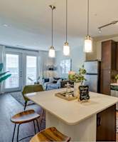 A kitchen with a white island and wooden chairs.
