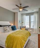 A bedroom with a white bed and a yellow comforter.