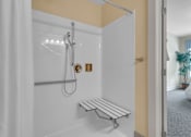 Thumbnail 25 of 54 - A white shower with a bench and a shower head.