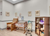 Thumbnail 32 of 54 - A baby nursery with a rocking chair, crib, and shelf with toys.