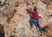 Thumbnail 8 of 16 - A man climbs a rock at Red Rock Apartments, Rapid City