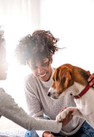 A woman and a child are petting a dog on a bed.