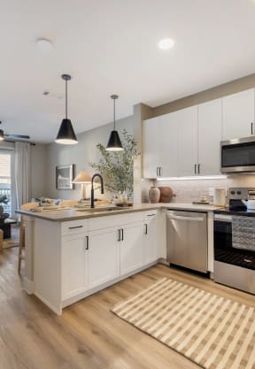 an open kitchen and living room with white cabinets and stainless steel appliances