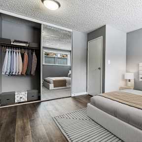 A bedroom with a large bed and a closet with clothes hanging.