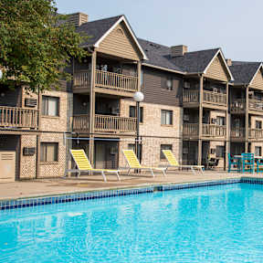 A large apartment complex with balconies and trees in the foreground.