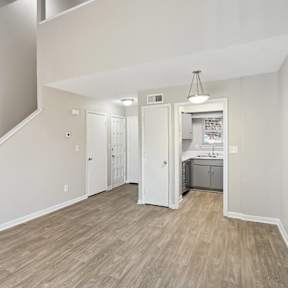 the living room and kitchen of a new home with white walls and wood flooring