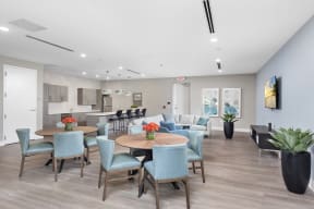 a common area with tables and chairs and a kitchen in the background