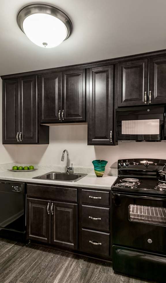 an updated kitchen with black appliances and dark wood cabinets