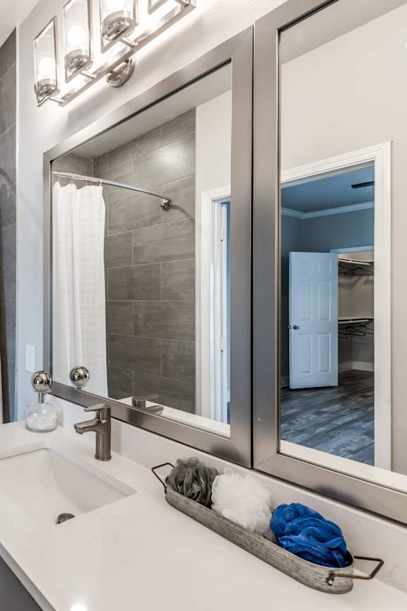 A modern bathroom with a white tub, sink, and a large mirror.