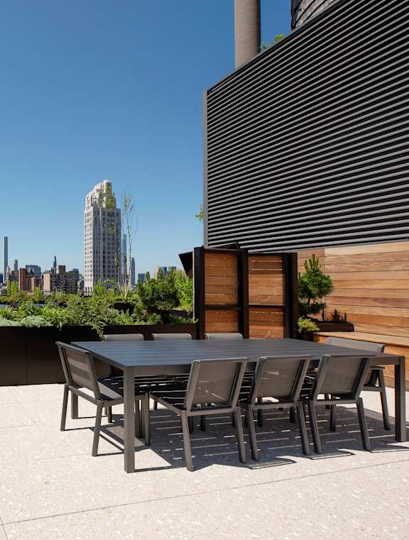 A rooftop patio with a table and chairs overlooking a city skyline.