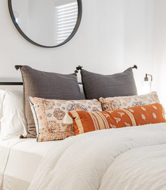 a bedroom with a bed with pillows and a mirror above it