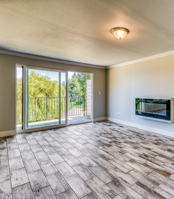 an empty living room with a sliding glass door and a tv